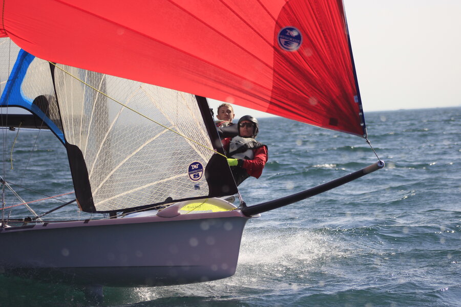 A 49er skiff sailing downwind under a red asymmetric spinnaker