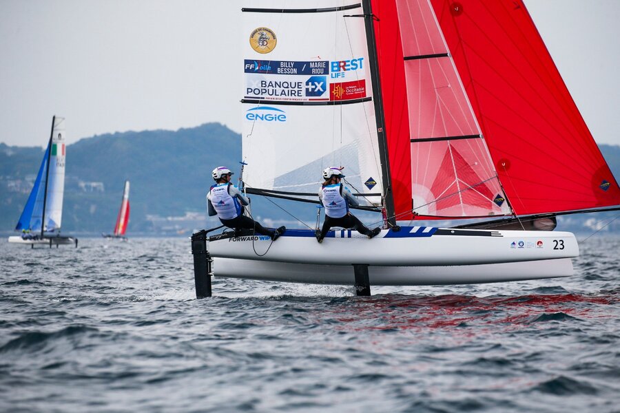 Two sailors racing a foiling Nacra 17 catamaran, hulls lifted clear of the water